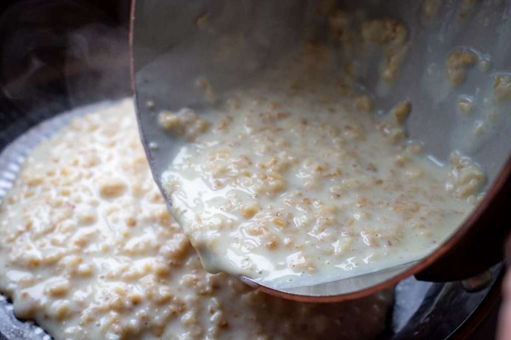 Pouring the oatmeal into a black bowl.