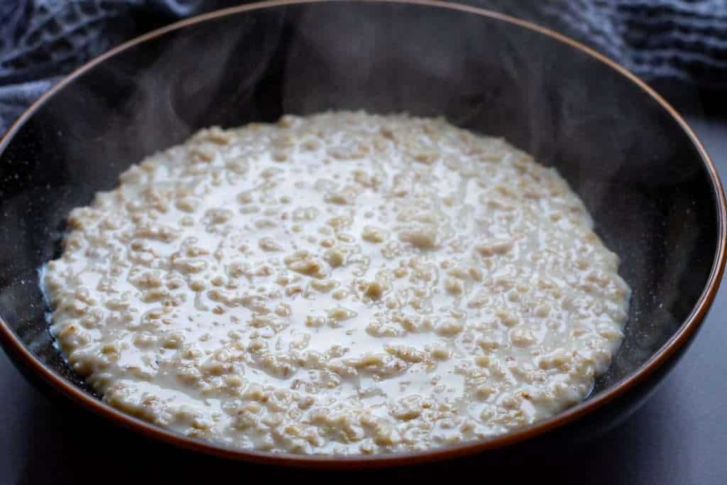 Cooked oatmeal in a black bowl.
