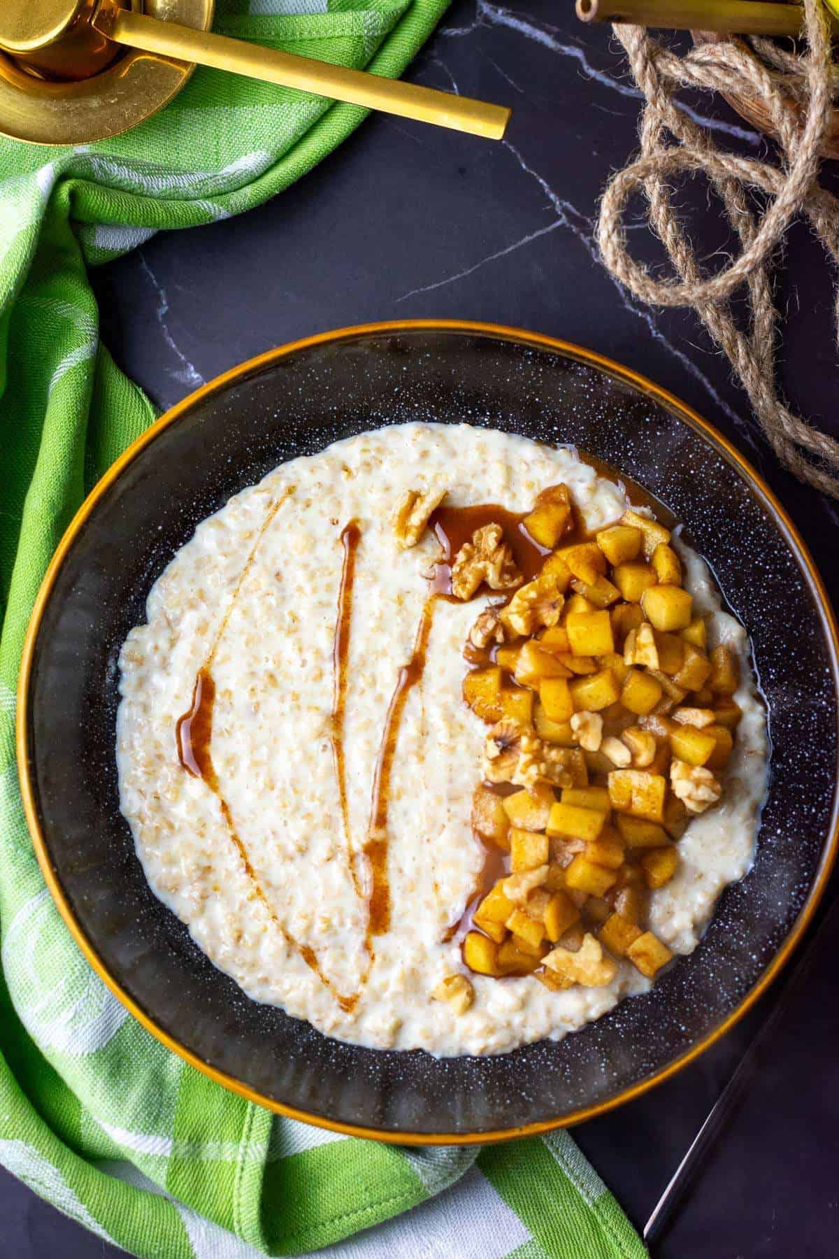 Cinnamon apple porridge in a black bowl.