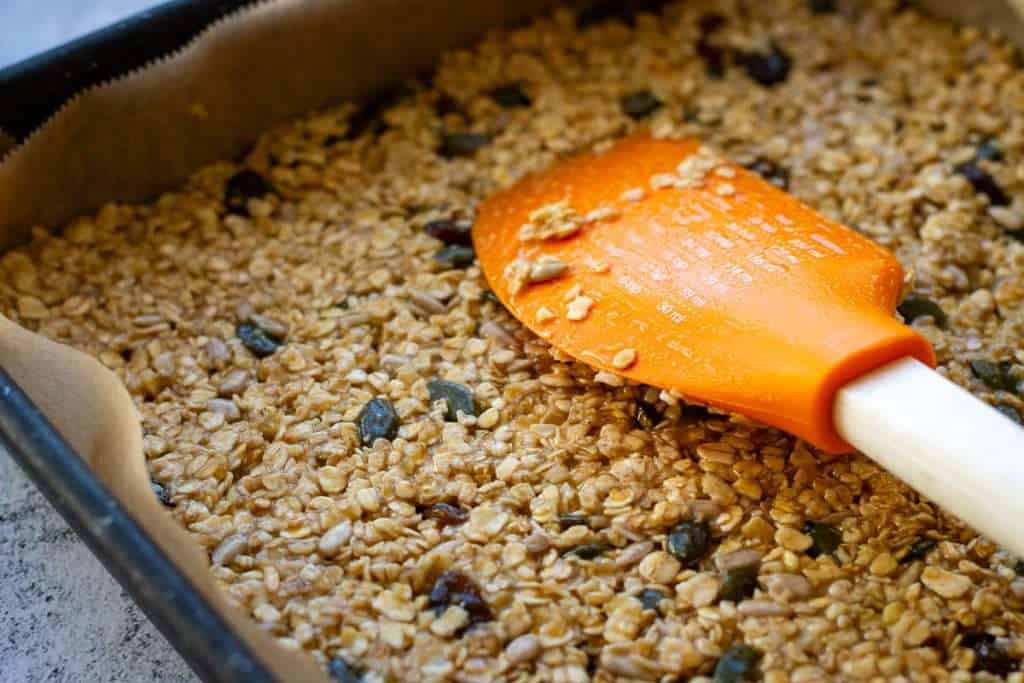 Pressing the oat mixture to the base with a spatula.