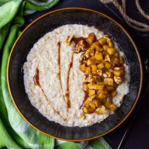Cinnamon apple porridge in a black bowl.