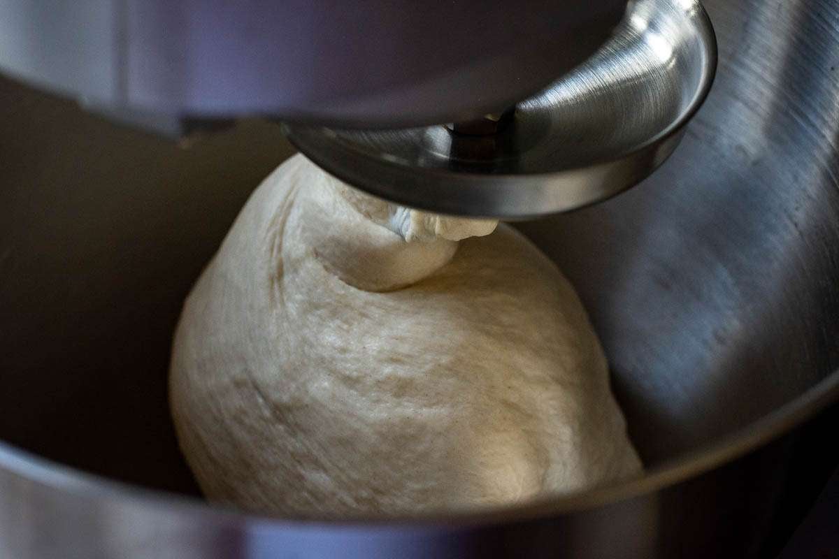 Sourdough wrapping around a dough hook attachment in a stand mixer.
