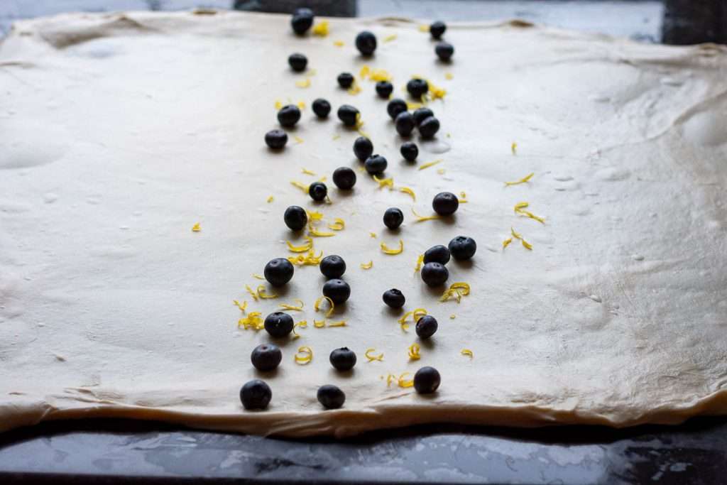 Thinly stretched sourdough with lemon zest and blueberries scaterref in the centre.