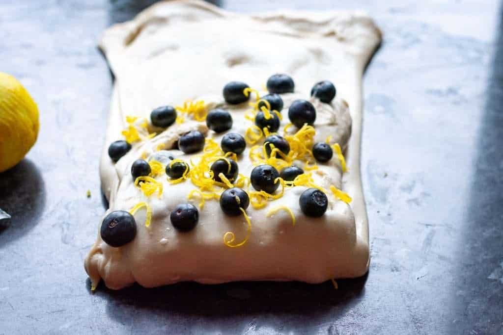 More blueberries and lemon zest scaterred on top of the dough.
