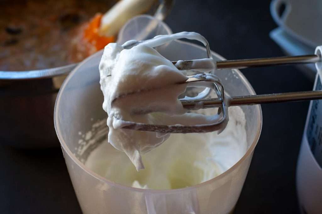 Whisked egg whites wrapping around electric mixer beaters.