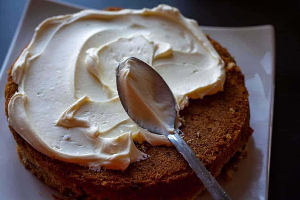 Spreading honey cream cheese frosting on the sourdough carrot cake.