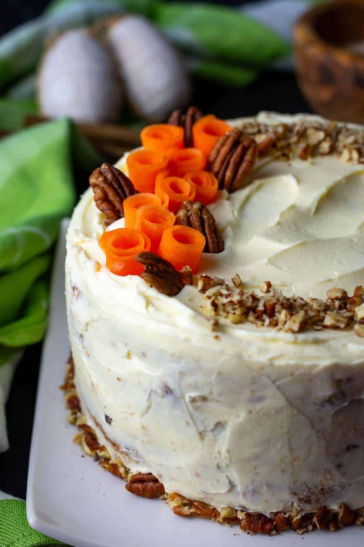 Sourdough carrot cake decorated with pecans and rolled up carrot slices.