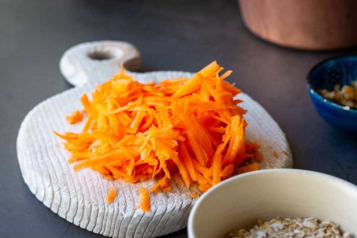 Coarsely grated carrot on a wooden chopping board.