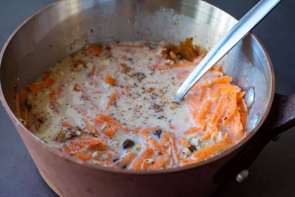 Carrot cake oatmeal ingredients mixed in a copper pan.