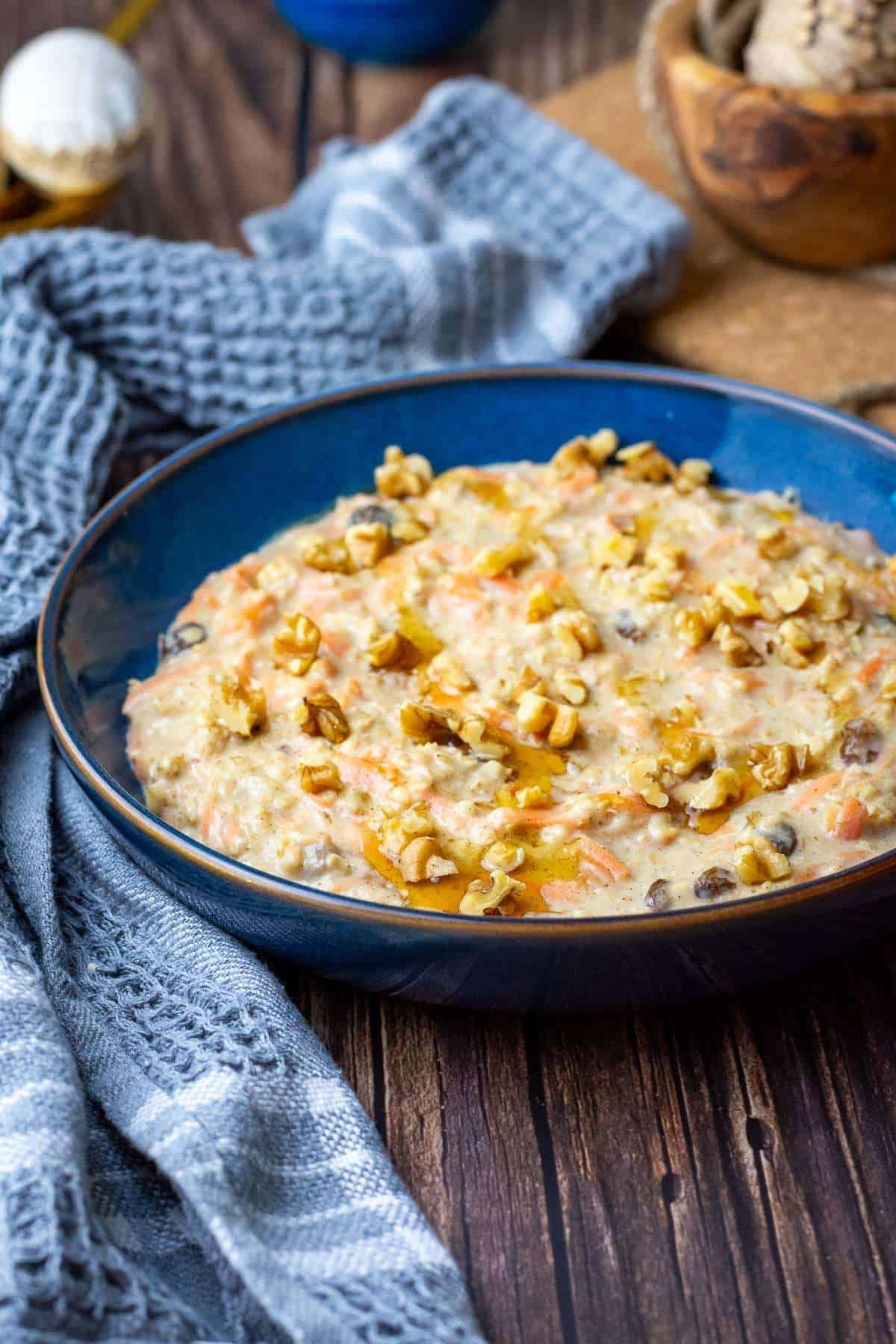 Carrot cake porridge topped with walnuts, and a drizzle of maple syrup.