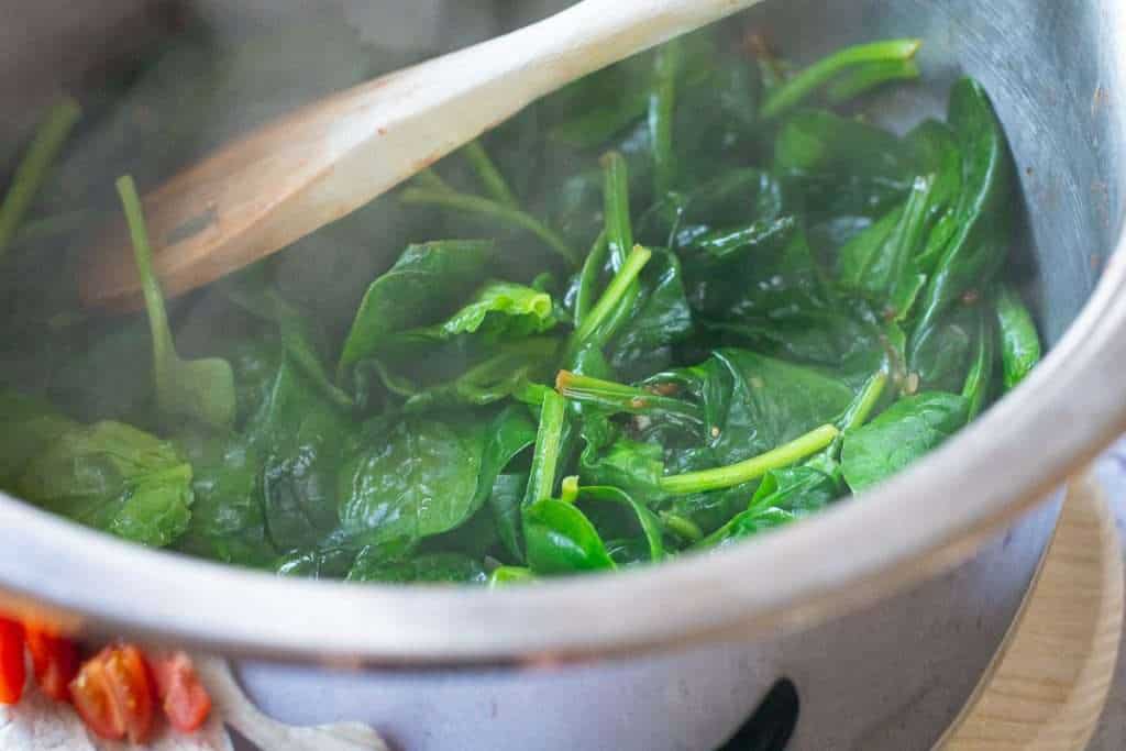 Winted baby spinach in a pan with onions.