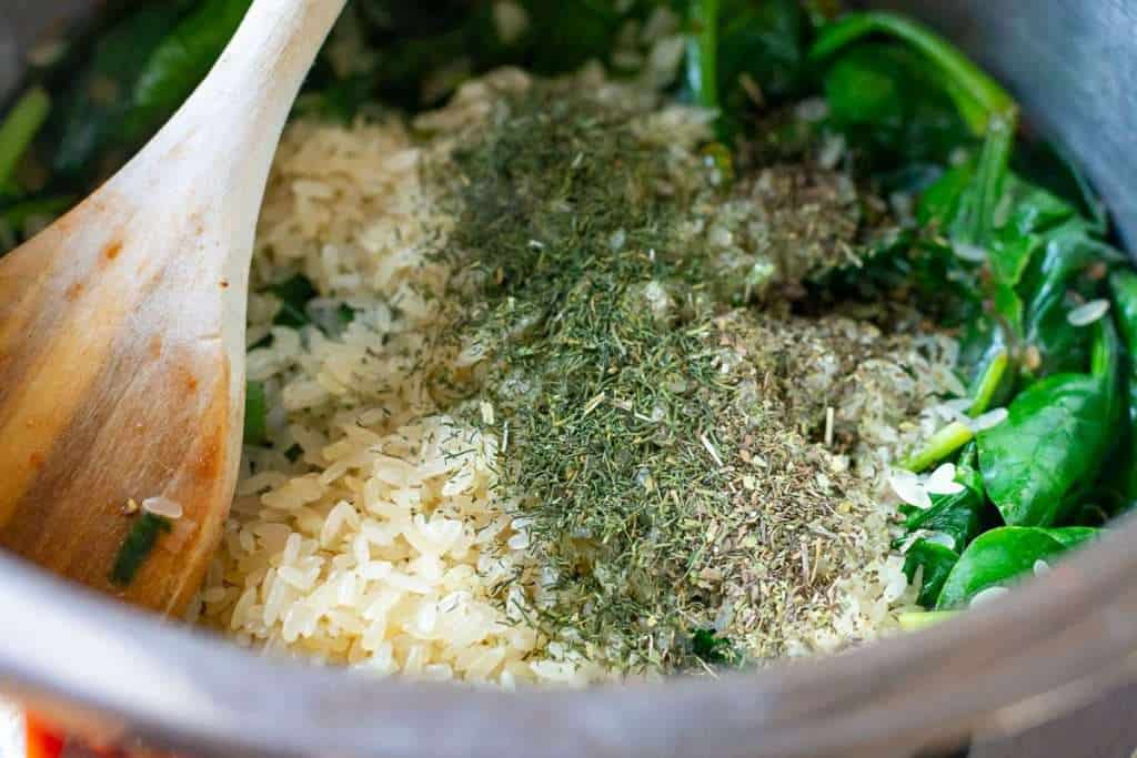 Rice and dried herbs added on top of the wilted spinach.