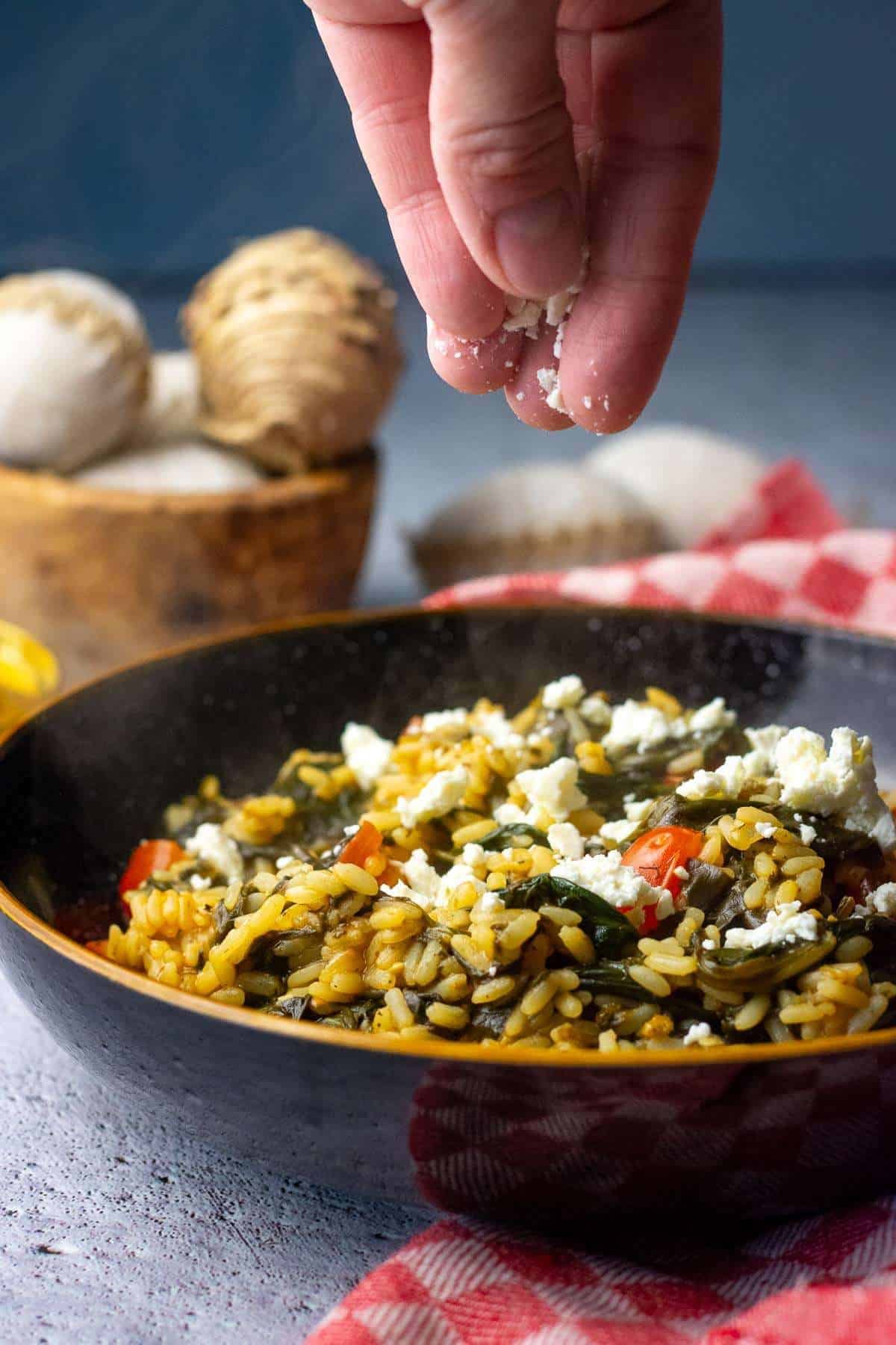 Scattering crumbled feta on top of spanakorizo.