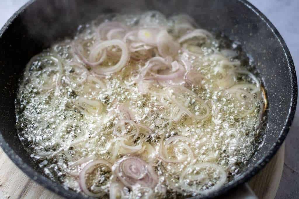 Shallot rings frying in hot oil.