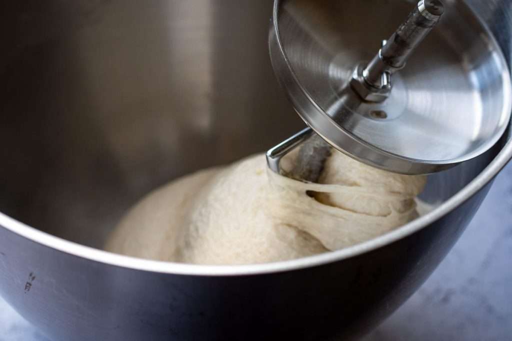 Smooth and elastic sourdough wrapping around the dough hook attachment in a stand mixer.