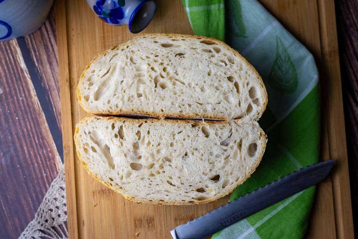 Same Day Sourdough Bread cut in half on a wooden chopping board.