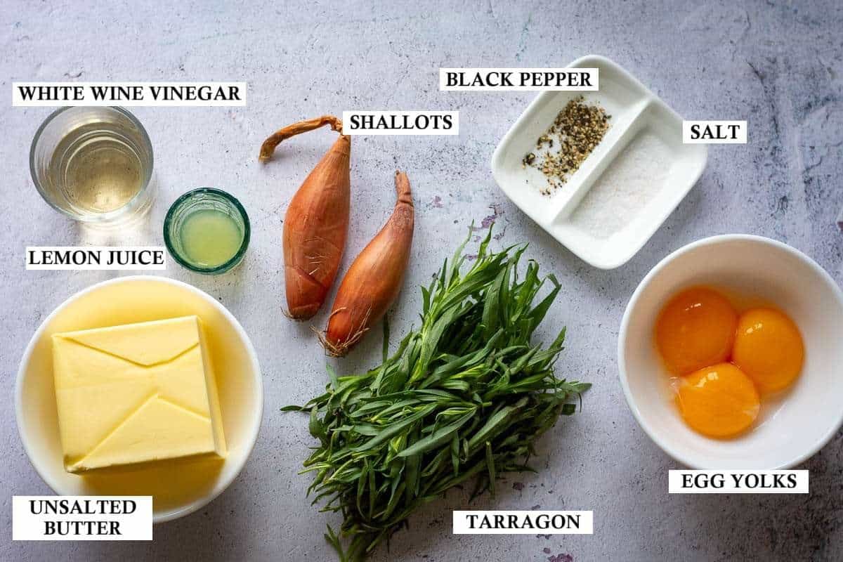 Ingredients for homemade bearnaise sauce on a light grey surface.
