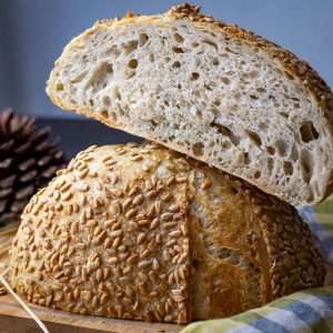 Sunflower Seed Sourdough Bread cut in half on a wooden board.