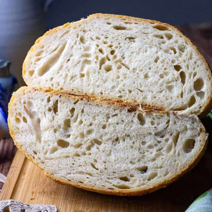 Same Day Sourdough Bread cut in half on a wooden chopping board.