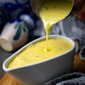 Bearnaise sauce is being poured into a gravy boat.