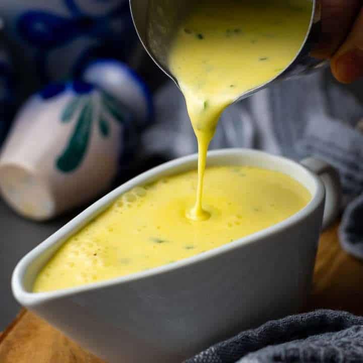 Bearnaise sauce is being poured into a gravy boat.
