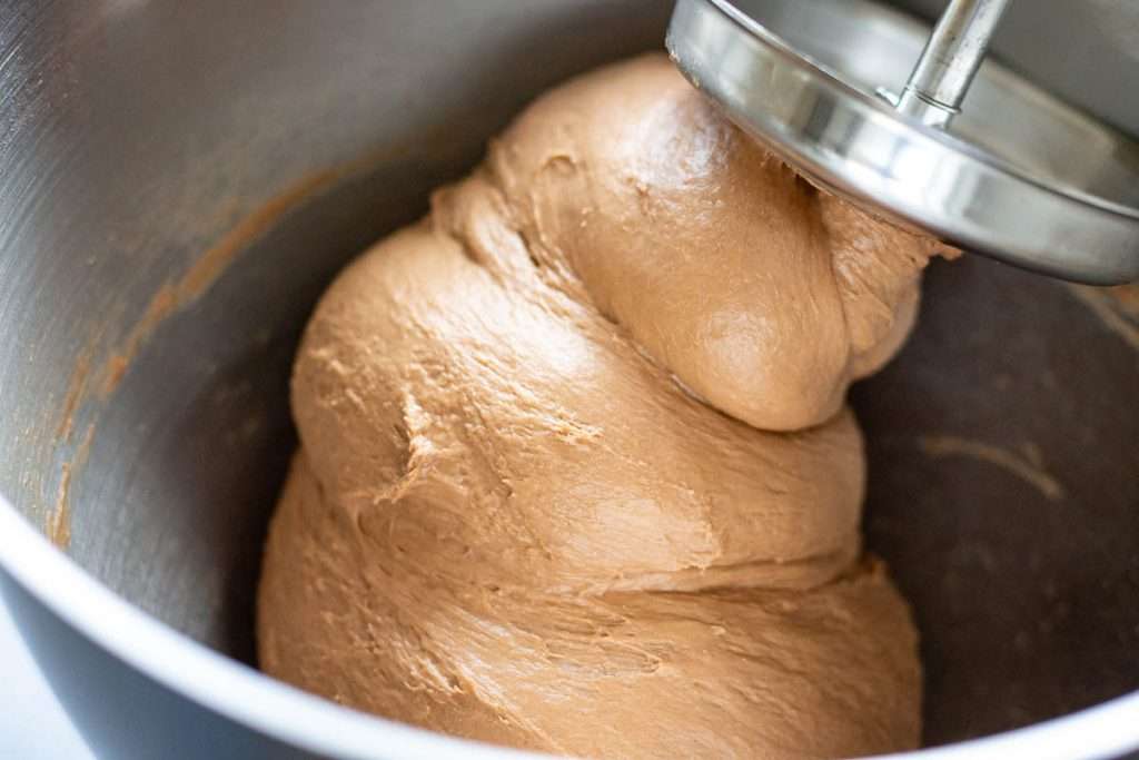 Chocolate hot cross bun dough wrapping around the dough hook attachment.