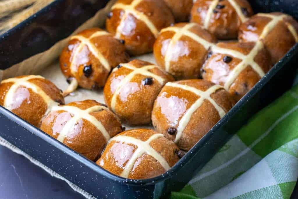 Glazed sourdough chocolate hot cross buns cooling in the baking tray.