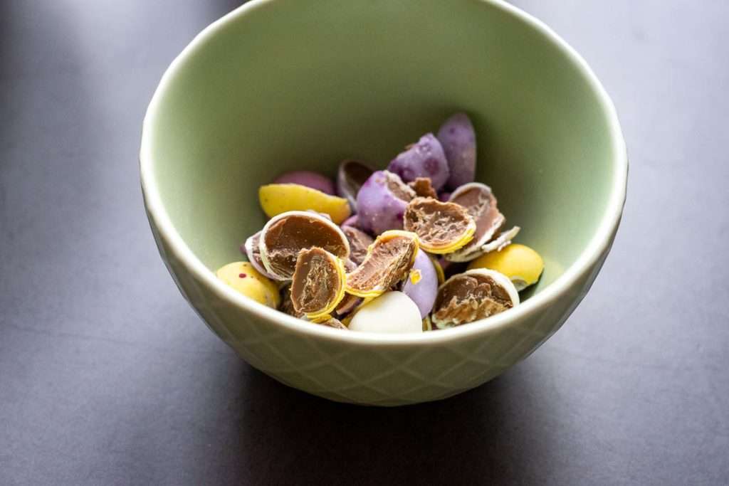 Crushed mini eggs in a palte green bowl reserved for topping.