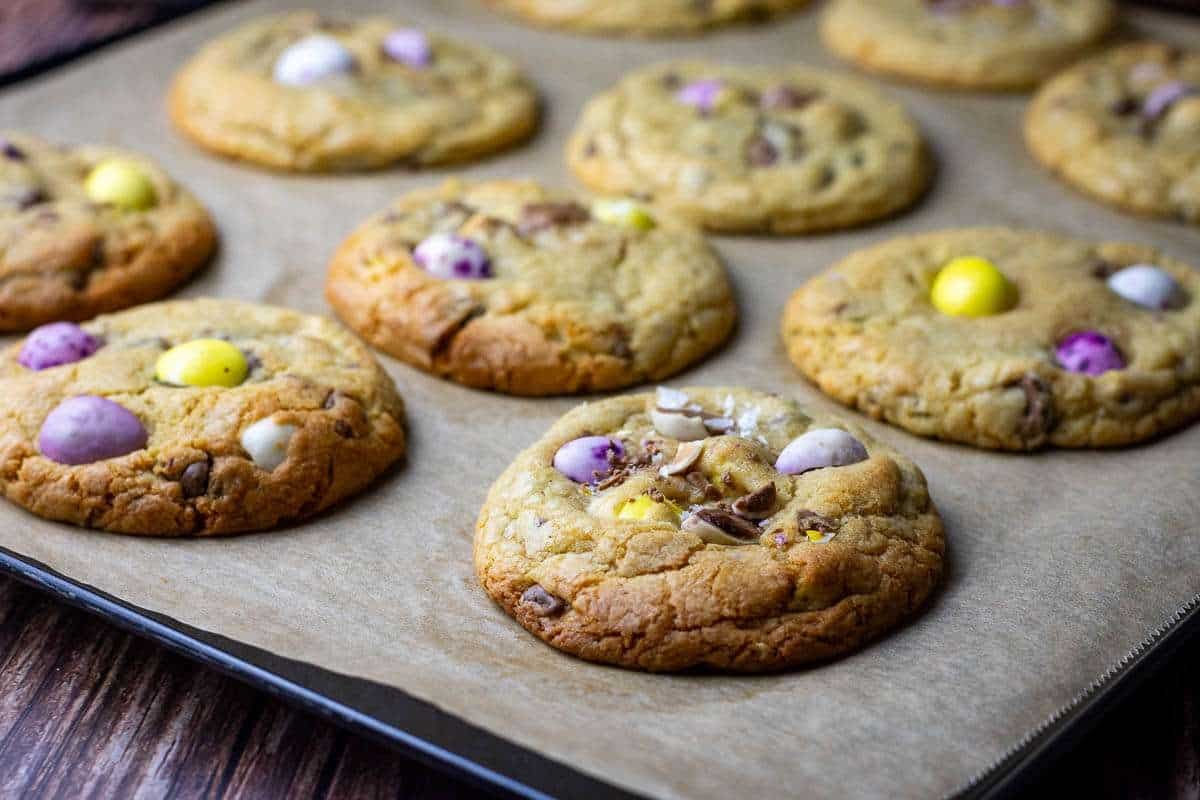 Bked easter cookies with mini eggs on a parchment paper lined baking sheet.