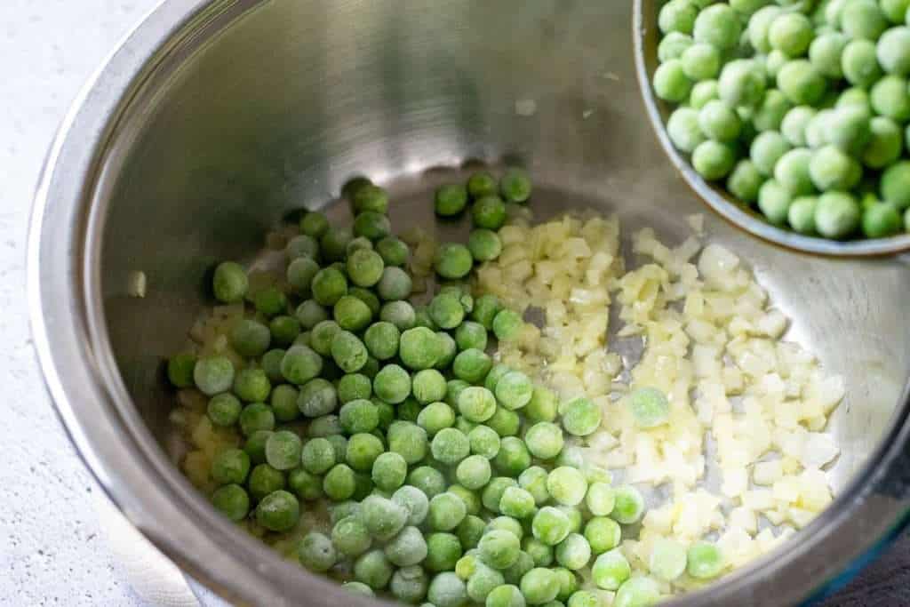 Frozen green peas added to the onion pan.