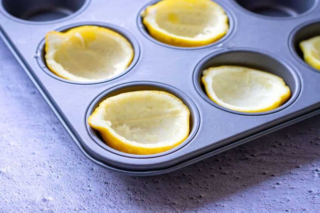 lemon peel halves arranged in a muffin tin.