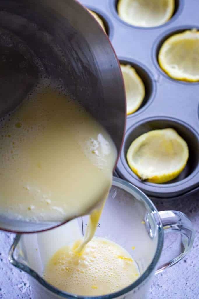 Pouring heated cream nad sugar over the lemon zest in a glass jug.