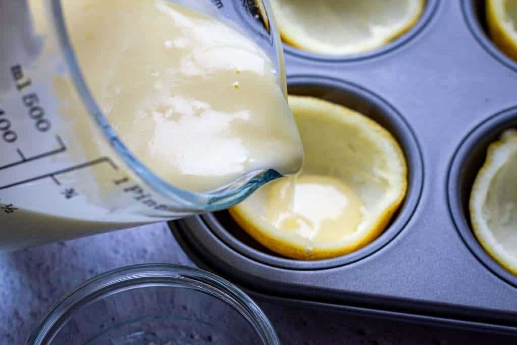 Pouring lemon posset mixture into the lemon peel halves.