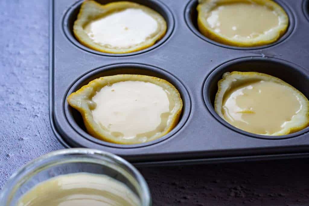 Filled lemon halves in a muffin tin.