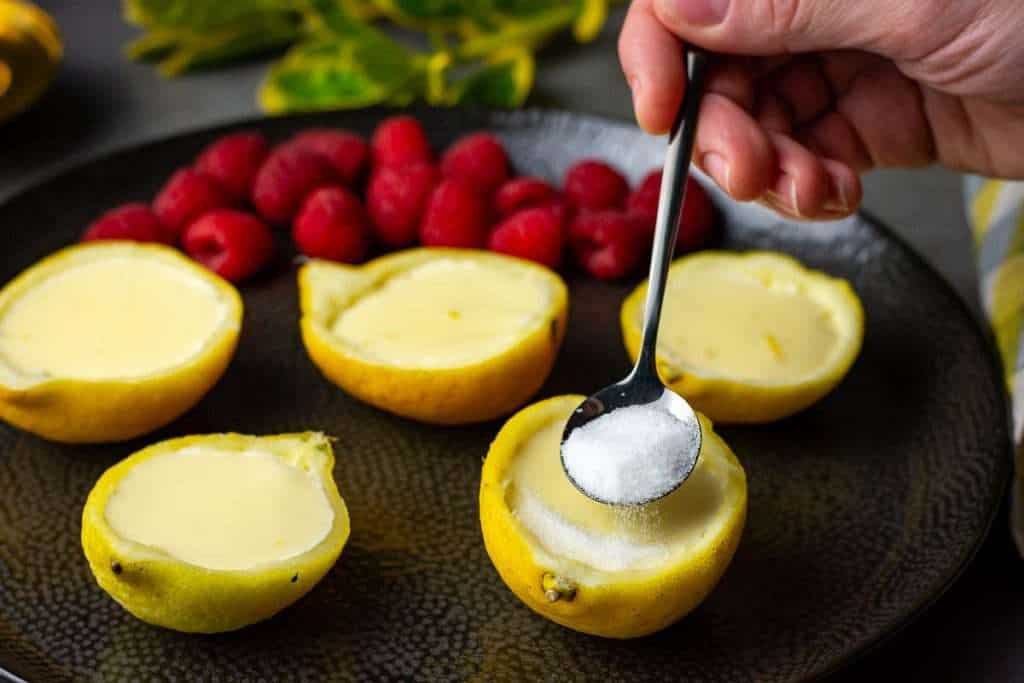 Sprinkling sugar on top of the lemon possets.