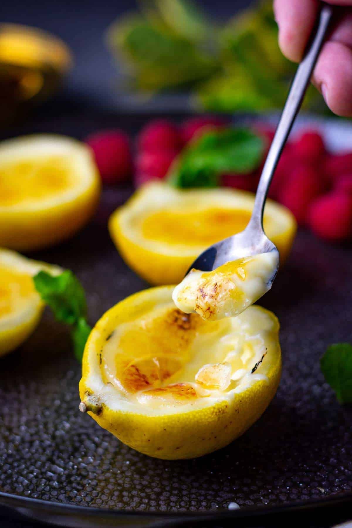 A spoonful of lemon posset brulee being taken out of the lemon peel half.