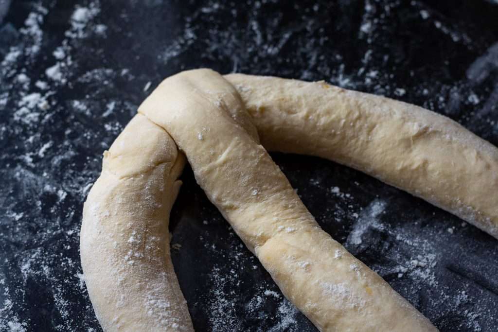 Three sourdough ropes for pane di pasqua attached at one end.