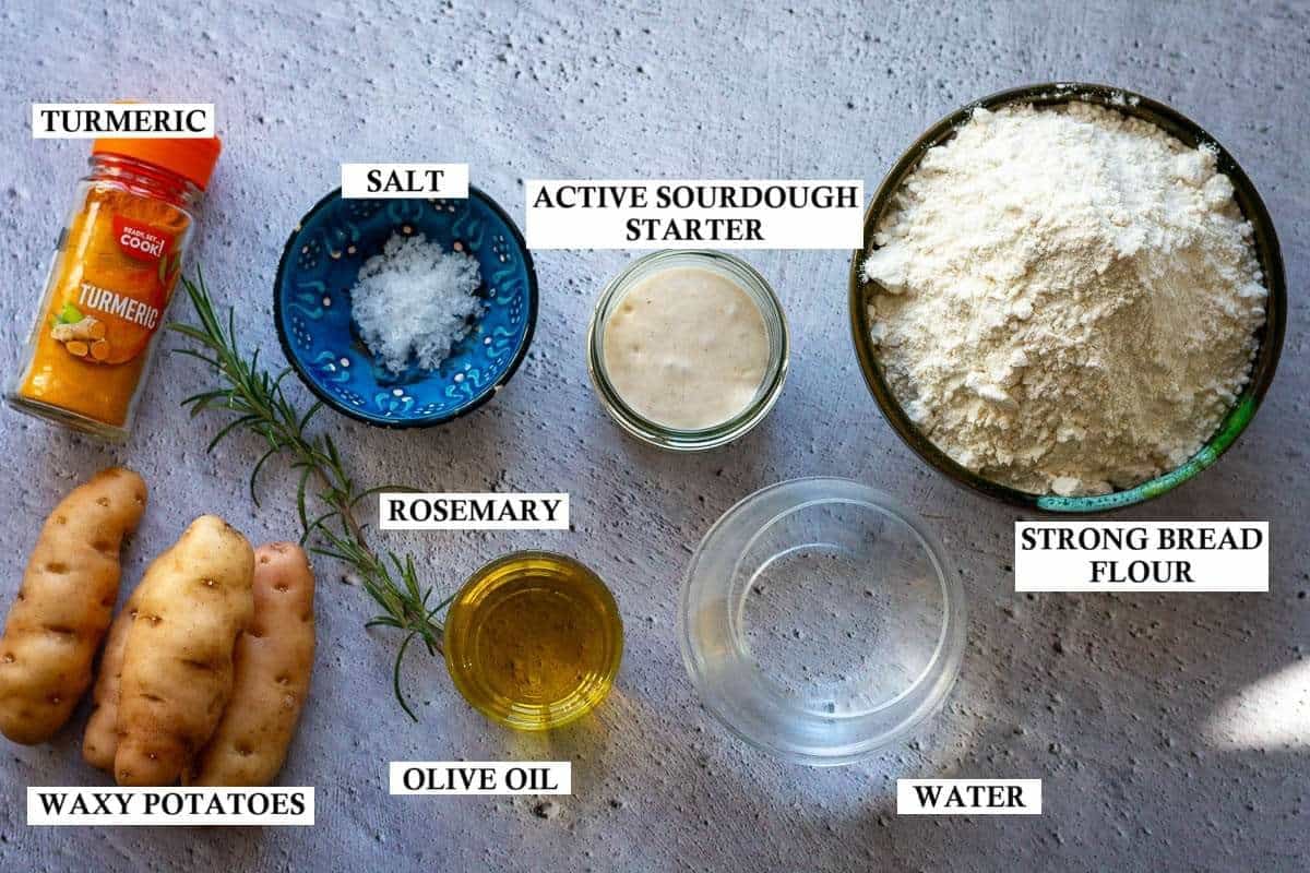 Ingredients for potato sourdough focaccia on a grey surface with labels.