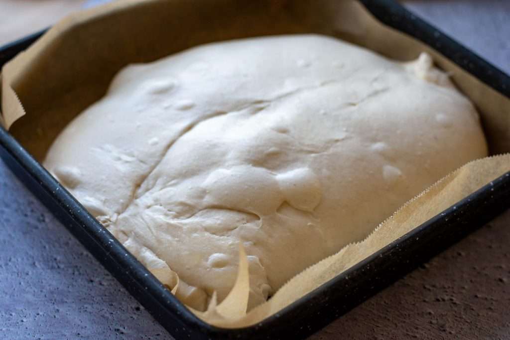 Sourdough focaccia turned out into a lined baking tray.