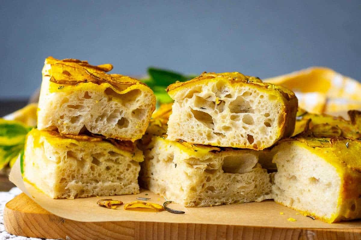 Slices of potato and rosemary focaccia on a wooden cutting board.