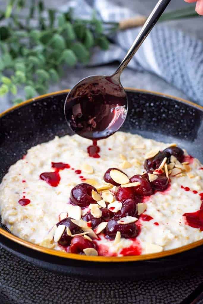Drizzling the juices from the cherry compote over the Cherry Bakewell Porridge.