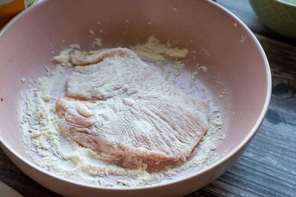 chicken cullet in a shallow bowl with flour.