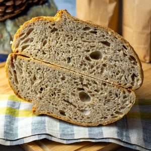 Barley Sourdough Bread cut in half on a checked tea towel.