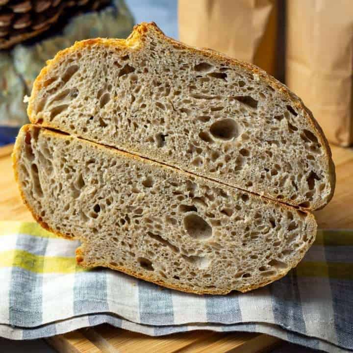 Barley Sourdough Bread cut in half on a checked tea towel.