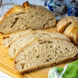 Half a loaf of French Sourdough Bread sliced on a wooden board.