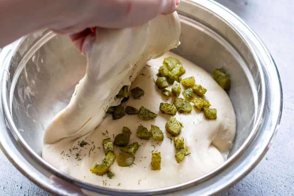 Stretching and folding the dough over the pickles.