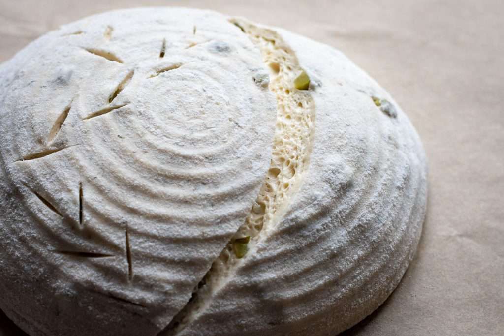 Scored sourdough bread on a piece of parchment paper.