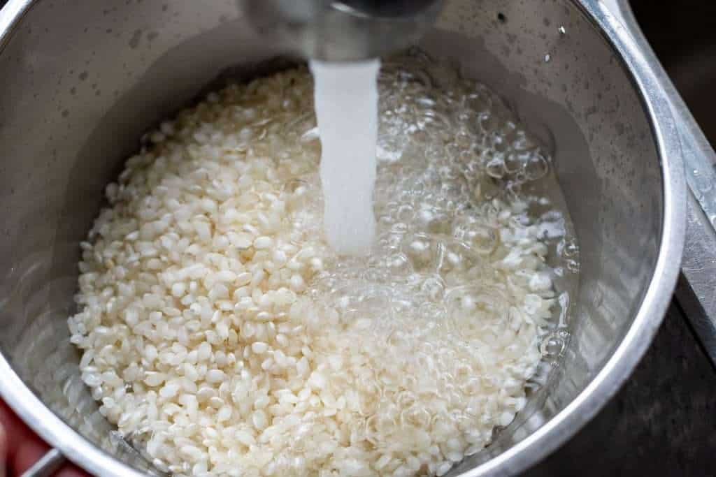 Rinsing rice in a colander with cold water.