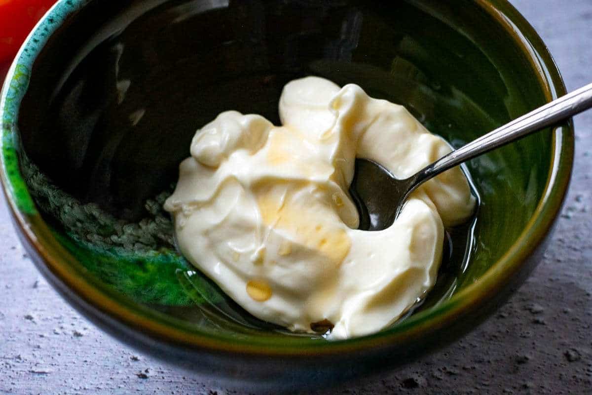 Mayonnaise with sesame oil in a small green bowl.