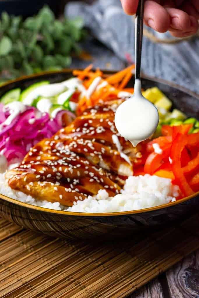 Drizzling sesame mayo dressing over the teriyaki chicken poke bowl.